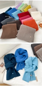 Detail showing soft ribbed knit texture and metallic logo tag on premium wool scarves
