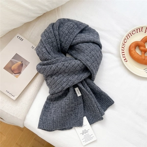 Detailed macro view of heavy dark grey wool scarf showing thick knitted texture and softness