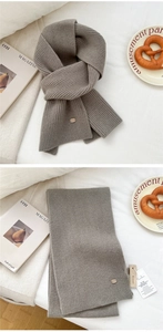 Close-up of dark grey ribbed knit wool scarf with leather brand tag and wood block