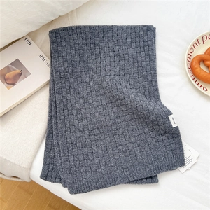 Detailed close-up of dark grey 100% wool knitted scarf with textured weave pattern