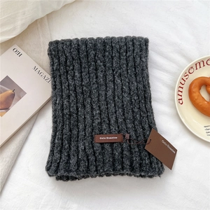 Detailed macro view of dark grey knitted infinity scarf with leather brand tag