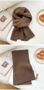 Detail of soft brown chunky rib-knit wool scarf with oval brand tag and paper label