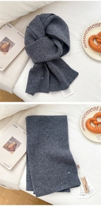 Macro detail of dark grey wool knit scarf showing ribbed texture and soft fabric quality