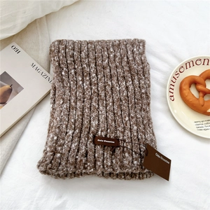 Close-up of thick knitted winter scarf with brown mixed texture and leather brand label
