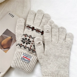 Detail of cream knit gloves featuring Nordic jacquard patterns and two-finger touch openings