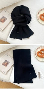 Close-up of soft black knit scarf with ribbed texture, decorative button and brand tags