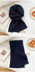 Detail of black ribbed knit wool scarf with elegant brand logo and premium wood tags