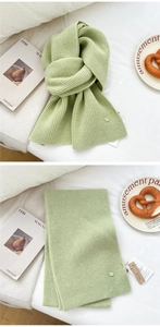 Detail showing soft light green knitted wool scarf texture with elegant decorative button