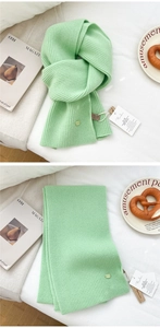 Detail of light green ribbed wool scarf with premium texture and minimalist brand tag
