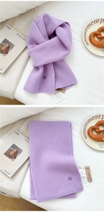 Detail view of purple ribbed knit wool scarf with brand tag and minimalist texture