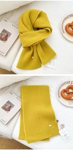Detail of mustard yellow knit scarf with ribbed texture and gold metal logo tag