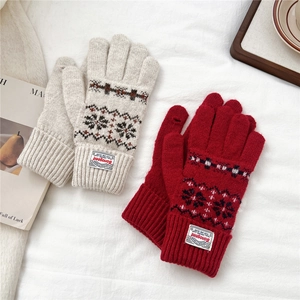 Detail of red and cream knit gloves with Nordic snowflake patterns and ribbed cuffs