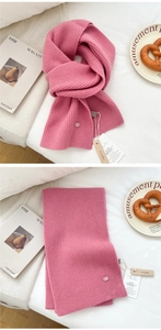 Detail of pink ribbed wool scarf with wooden moth repellent charm and authentic woven labels