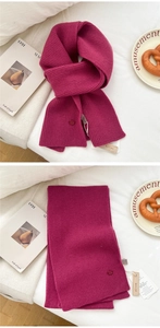 Detail of rose red knit wool scarf showing chunky texture and 100% wool product tag