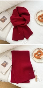 Close-up of dark red ribbed wool scarf with premium logo detail and soft knitted texture