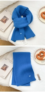 Detail view of a bright blue chunky knit wool scarf with vertical ribbed texture and tags