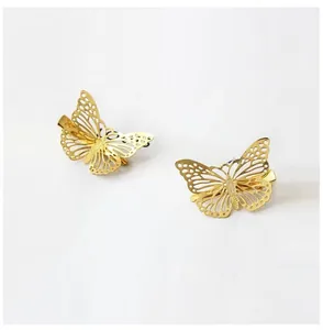 Macro detail of gold butterfly hair clips with intricate hollow metal wings pattern