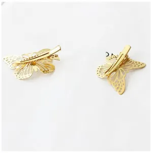 Close-up of golden hollow butterfly hair clips with intricate metal cutouts