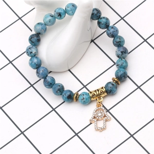 Détail des perles bleues tachetées et de la main de fatma dorée sur le bracelet