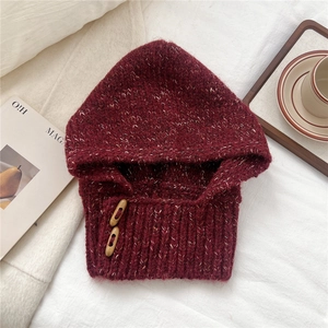 Close-up of burgundy knit balaclava featuring wooden buttons and warm ribbed texture