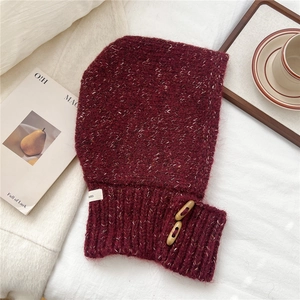Detail of burgundy knit balaclava with wooden buttons on a textured winter background