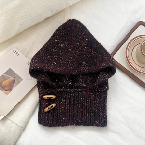 Detail of burgundy knitted hooded scarf with wooden buttons on a cozy white background