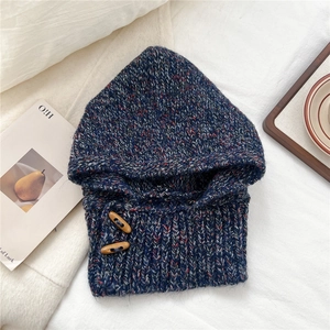 Detail of blue and red knit balaclava hat with wood buttons on textured background