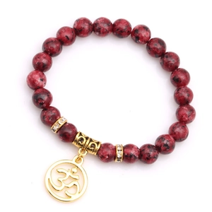 Gros plan du bracelet en jaspe rouge avec pendentif OM doré et anneaux en cristal