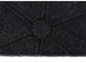 Detailed top view of black wool flat cap showing six-panel stitching and center button