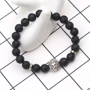 Detailed view of black volcanic lava stone beads and silver lion head charm on a hand model