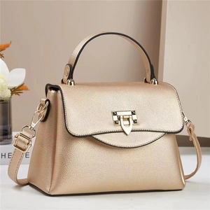 Close-up of golden textured leather handbag featuring a V-shaped metal buckle with rivets