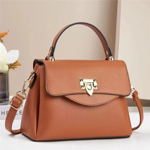 Detail of brown leather bag with golden geometric shield lock and textured finish