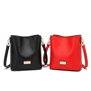 Detail view of black and red bucket bags with leather texture and golden metal hardware buckles