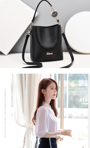 Close-up of black bucket bag with golden hardware and detailed hanging cat charm