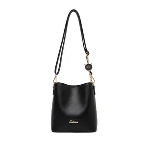 Close-up of black PU leather bucket bag with golden logo plate and cat charm detail