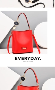 Detail view of red synthetic leather bucket bag with gold hardware and cat-shaped charm