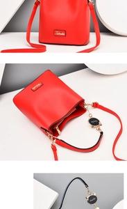 Detail of red PU leather bucket bag featuring a cat-shaped pendant and golden logo