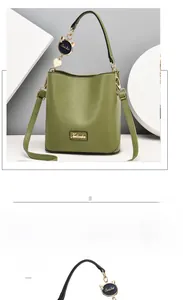 Detailed view of sage green bucket bag with metallic logo and black cat-ear charm