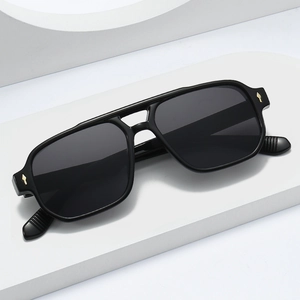 Square double bridge black sunglasses with gold metal accents on a white stand
