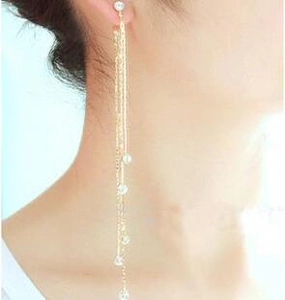 Detailed close-up of long gold tassel earrings with sparkling crystal accents on model