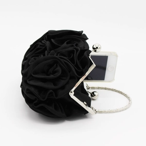 Detail of black satin evening bag featuring 3D roses and a silver circular handle