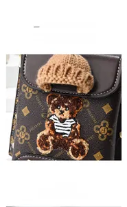 Close-up of brown crossbody phone bag featuring vintage floral print and bear embroidery