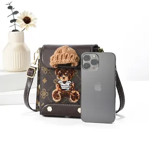 Detail view of brown PU leather crossbody bag with teddy bear charm and gold metal buckle