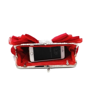 Detail of red pleated satin clutch with rhinestone bow clasp and interior phone compartment