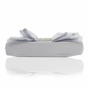 Detailed view of white satin evening clutch featuring large bow and rhinestone center
