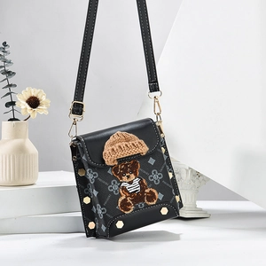 Black leather crossbody bag with letter patterns and 3D bear embroidery on white stand