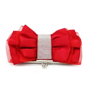 Close-up of red silk bow evening bag featuring a sparkling rhinestone centerpiece
