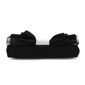 Detail of elegant black evening clutch featuring a large layered bow and sparkling rhinestones