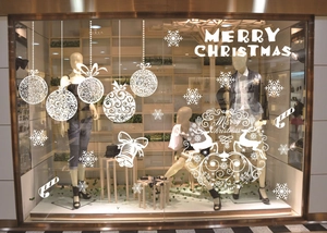 Close-up of white Christmas window stickers with snowflake and deer designs in a shop display
