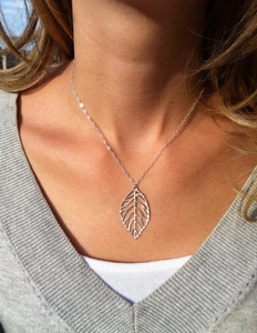 Close-up of silver leaf pendant necklace on model to show texture and wearing effect